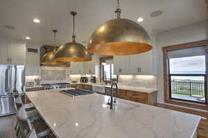 Kitchen with a kitchen island with sink, a sink, appliances with stainless steel finishes, and dark wood-style floors
