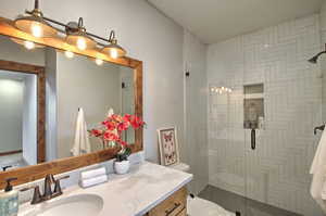 Full bath with toilet, vanity, and a shower stall