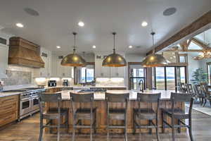 Kitchen featuring double oven range, custom range hood, light countertops, and a center island with sink