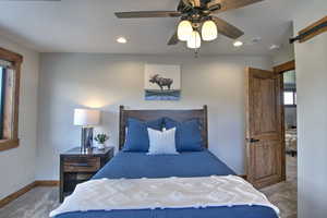 Carpeted bedroom featuring a ceiling fan, a barn door, baseboards, visible vents, and recessed lighting