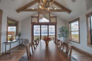 Dining area featuring dark wood-style floors, a chandelier, beamed ceiling, and a wealth of natural light