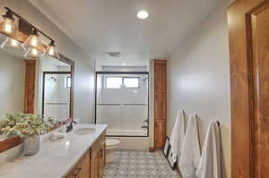 Full bath featuring visible vents, combined bath / shower with glass door, toilet, recessed lighting, and vanity