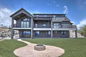 Back of property with an outdoor fire pit, a lawn, a shingled roof, and a patio area