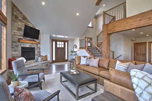 Living room with recessed lighting, a stone fireplace, stairs, and wood finished floors