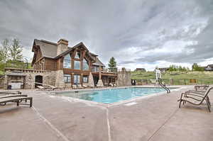 Pool with fence, an outdoor stone fireplace, a patio area, and stairway