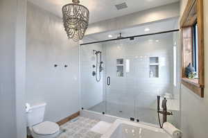 Full bath with toilet, baseboards, a stall shower, visible vents, and a notable chandelier
