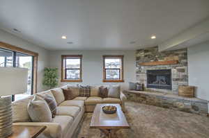 Carpeted living area with recessed lighting, a stone fireplace, and visible vents