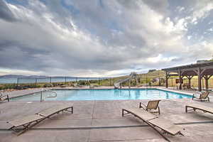 Community pool featuring fence, a mountain view, a water slide, and a patio area