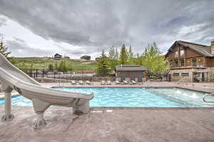 Community pool featuring a patio, fence, and a water slide