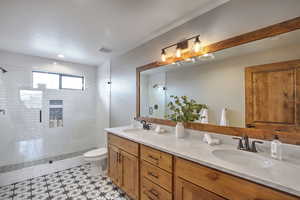 Bathroom with visible vents, a sink, double vanity, and a shower stall