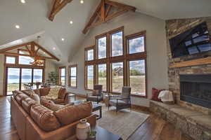Living area featuring a fireplace, high vaulted ceiling, hardwood / wood-style flooring, and an inviting chandelier