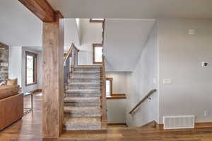 Stairs with beamed ceiling, visible vents, and wood finished floors