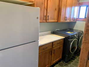 Washroom with cabinet space, dark tile patterned floors, and washer and dryer