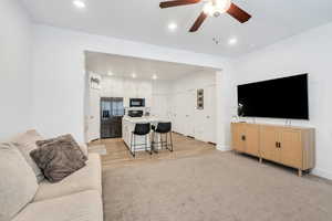 Living area with a ceiling fan, light colored carpet, recessed lighting, baseboards, and light wood-style flooring