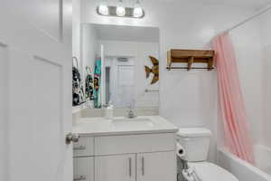 Bathroom with shower / bath combination with curtain, toilet, and vanity