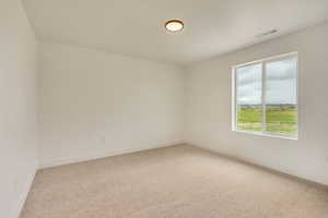 Carpeted empty room featuring visible vents and baseboards