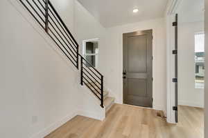Entrance foyer featuring stairway, light wood finished floors, and baseboards