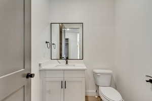 Bathroom featuring baseboards, toilet, and vanity