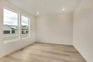 Empty room featuring baseboards, light wood finished floors, and recessed lighting