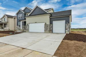 Craftsman-style home featuring board and batten siding, an attached garage, stone siding, and driveway