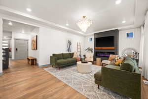 Living room with a raised ceiling, recessed lighting, a notable chandelier, and light wood-type flooring