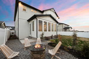 Back of house featuring stucco siding, a fire pit, a fenced backyard, and a lawn