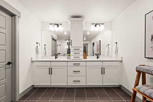 Master suite with tile patterned flooring, a sink, double vanity, and baseboards