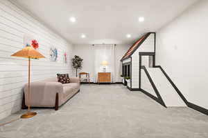 Living room featuring baseboards, wood walls, carpet floors, and recessed lighting