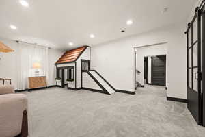 Living room with baseboards, a barn door, recessed lighting, and light carpet
