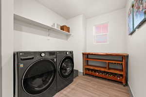 Laundry area featuring independent washer and dryer, baseboards, laundry area, and wood finished floors
