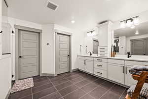 Master suite with double vanity, a tile shower, tile patterned floors, and a sink