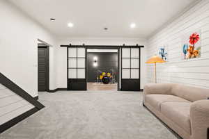 Living room with baseboards, a barn door, recessed lighting, and carpet