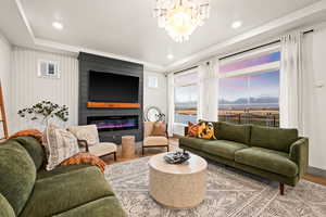 Living room featuring a large fireplace, wood finished floors, recessed lighting, and chandelier