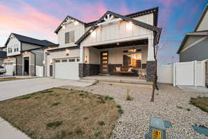 View of front of home featuring driveway, a gate, covered porch, stone siding, and board and batten siding