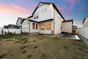 Back of house  with a fenced backyard, lawn,  patio, board and batten siding, and built in trampoline.