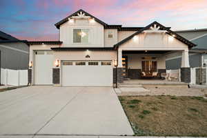 View of front of property featuring driveway, stone ,board and batten siding, and a porch swing.