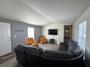 Living area with vaulted ceiling, carpet, and a textured ceiling