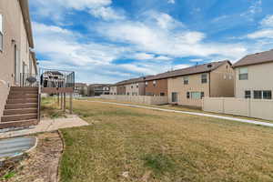 View of yard featuring a residential view, a wooden deck, stairs, and fence
