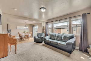 Living room with baseboards, a notable chandelier, and carpet