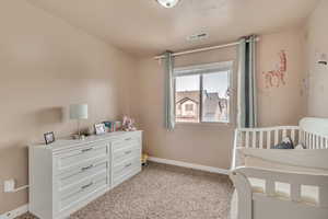 Bedroom with baseboards, visible vents, and light carpet