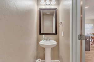 Bathroom with a sink, a textured wall, and wood finished floors