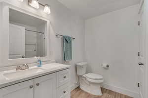 Full bathroom with a shower, vanity, toilet, baseboards, and wood finished floors