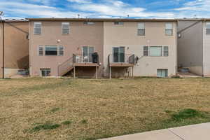 Rear view of property featuring a lawn, stucco siding, and stairs