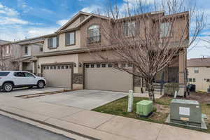 View of front of home with concrete driveway, stucco siding, central air condition unit, stone siding, and a garage