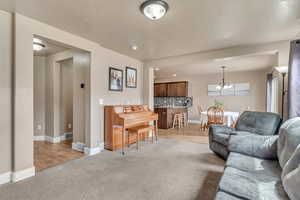 Living area featuring baseboards, visible vents, an inviting chandelier, and light colored carpet