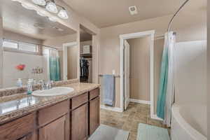 Bathroom with vanity, a walk in closet, baseboards, visible vents, and shower / bath combination with curtain