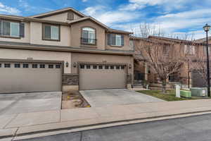 View of front of property featuring stucco siding, an attached garage, stone siding, and concrete driveway