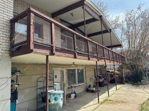 Back of property with brick siding, covered deck and covered patio