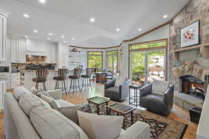 Living area with a fireplace, alder floors, vaulted ceiling, and kitchen