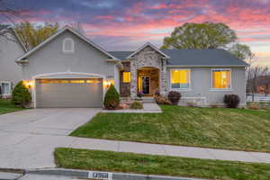 View of front of property featuring concrete driveway, stucco siding, an attached garage, and a lawn